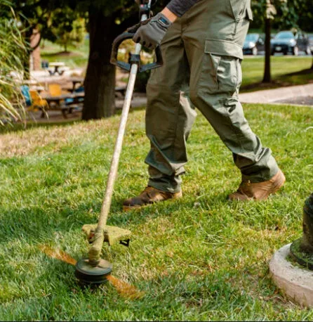 An ETA Outdoor Services Employee trimming around yard obstacles to finish a scheduled weekly lawn mowing visit in Bay City before more property maintenance in Essexville, Midland and Auburn Michigan