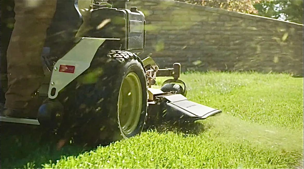 An ETA Outdoor Services Employee Mowing A Beautifully Landscaped Lawn At A Weekly Lawn Care Customer's Home in Midland Michigan